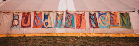 Flags on the side of a tent that spell out Buddhafield