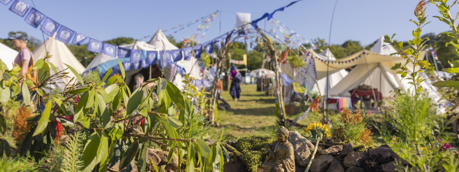 Buddha by a pond with a festival in the background