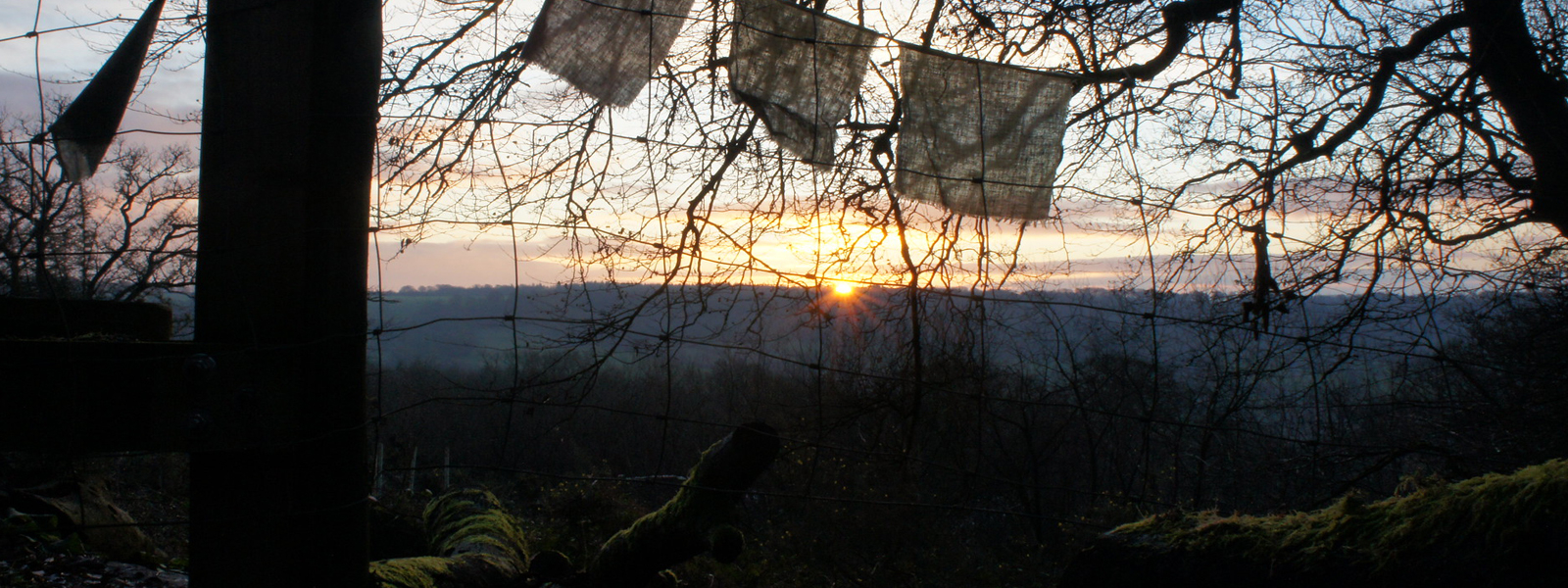 Prayer flags in front of a valley with a beautiful sun rising over the distant hill